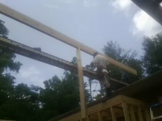 Carpenter setting a ridge beam over a new addition frame — Ice Dam Removal by Roofing Brothers in Fort Blackmore