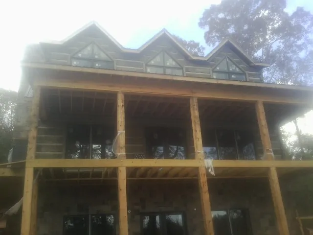 Dormers and porch framing on a large log home under construction — Roof Coating work by our crew in Fort Blackmore