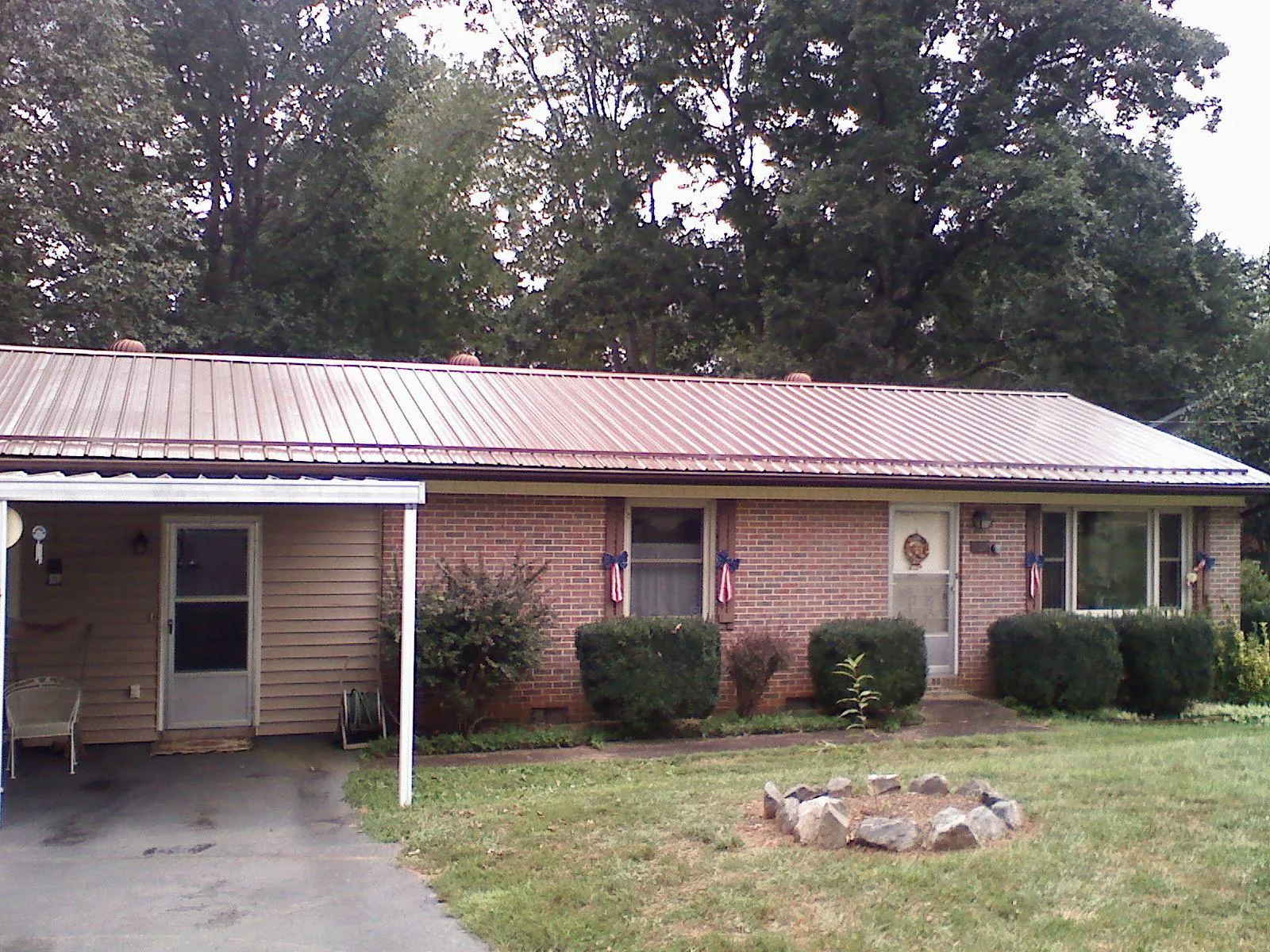 Bronze metal roof and carport on a brick ranch home — Roof Repair work by our crew in Fort Blackmore