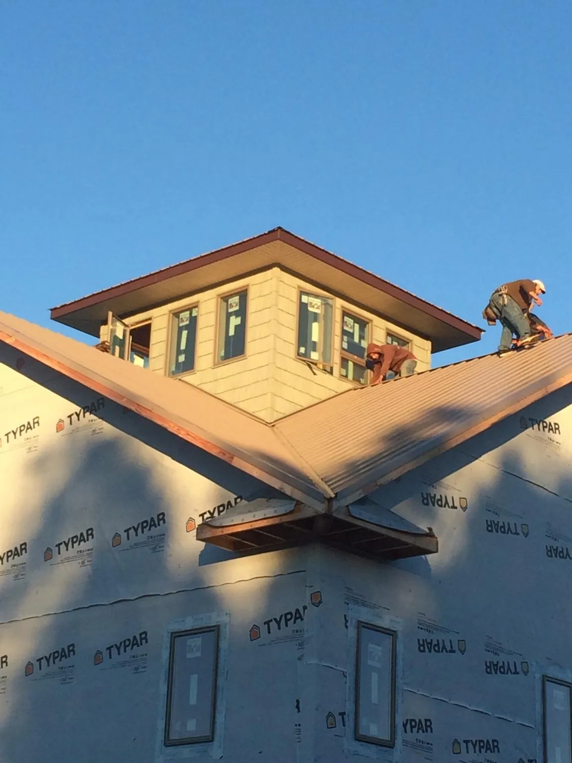 Roofers working around a rooftop cupola on a new metal roof at sunset — Roof Waterproofing in Fort Blackmore by Roofing Brothers